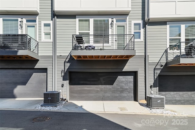 view of property featuring concrete driveway, an attached garage, and central air condition unit