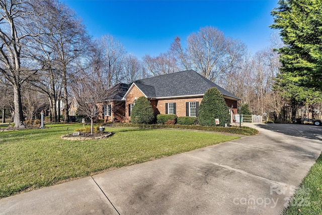 view of front of property featuring concrete driveway, brick siding, a front lawn, and roof with shingles