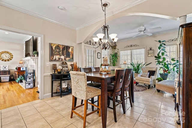 dining area featuring ceiling fan with notable chandelier, crown molding, and light tile patterned floors