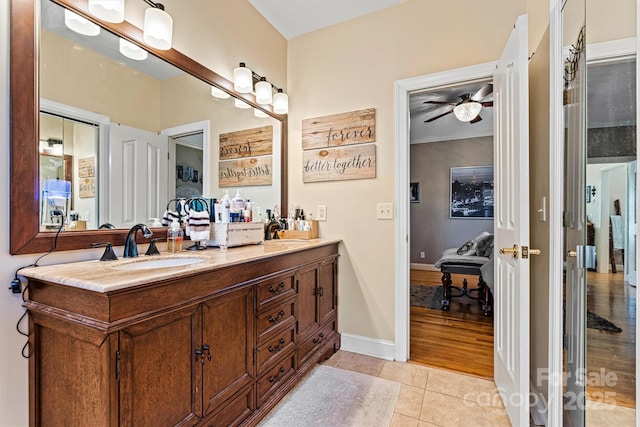 full bath featuring double vanity, a ceiling fan, a sink, tile patterned flooring, and baseboards