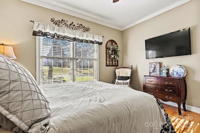 bedroom with baseboards, ornamental molding, ceiling fan, and wood finished floors