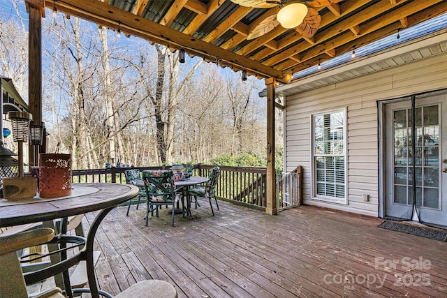 wooden terrace with a ceiling fan and outdoor dining area