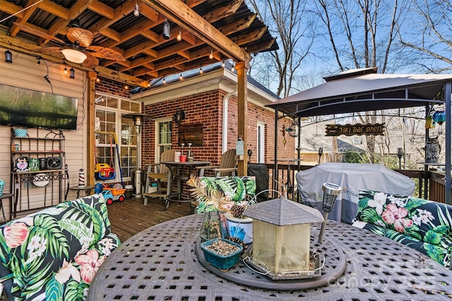 view of patio featuring outdoor dining area, a deck, and a gazebo