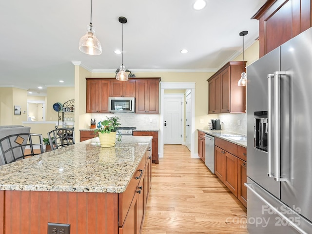 kitchen with appliances with stainless steel finishes, ornamental molding, decorative light fixtures, light stone countertops, and light wood-style floors