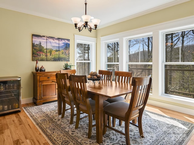 dining area featuring wine cooler, crown molding, light wood finished floors, an inviting chandelier, and baseboards