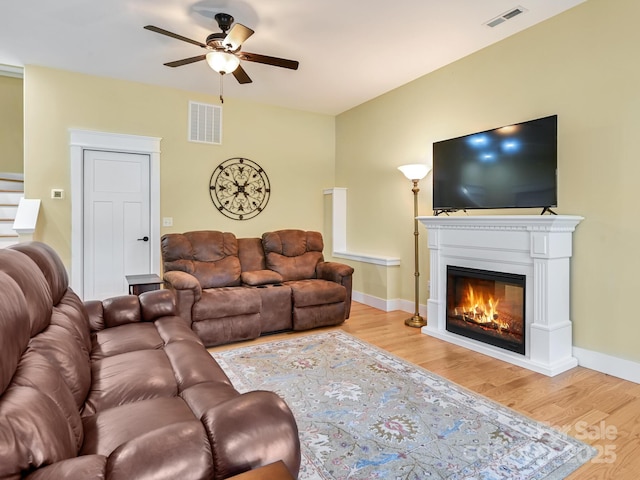 living room with a glass covered fireplace, wood finished floors, and visible vents