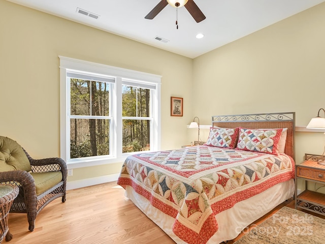 bedroom featuring visible vents, ceiling fan, baseboards, and wood finished floors