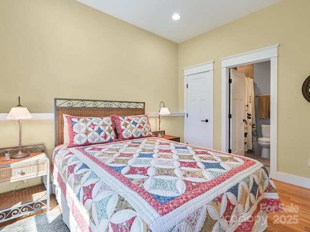 bedroom with recessed lighting, connected bathroom, baseboards, and wood finished floors