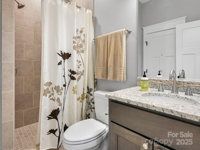 bathroom with a tile shower, vanity, and toilet