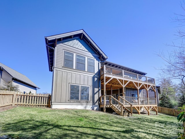 back of property with a deck, board and batten siding, a fenced backyard, and a lawn