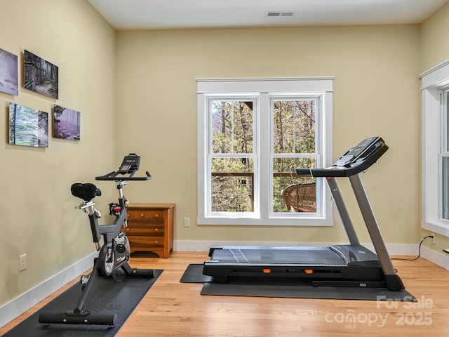 workout room with baseboards, visible vents, and wood finished floors