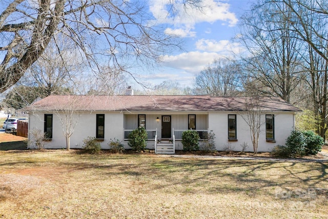 ranch-style house featuring a porch, a chimney, and a front lawn