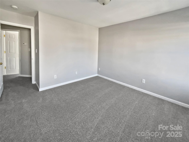 empty room featuring dark colored carpet and baseboards