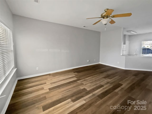 unfurnished room featuring ceiling fan, dark wood-type flooring, and baseboards