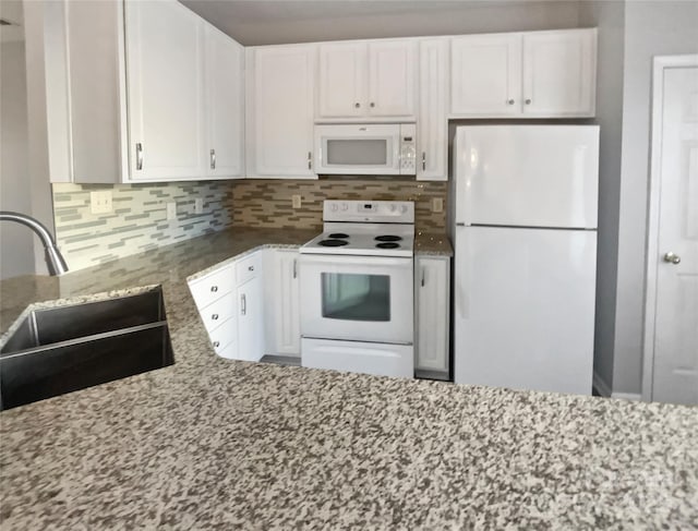 kitchen featuring white appliances, a sink, light stone countertops, and white cabinets