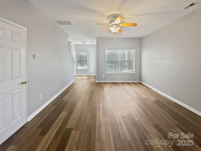 spare room with dark wood-style flooring, visible vents, and baseboards