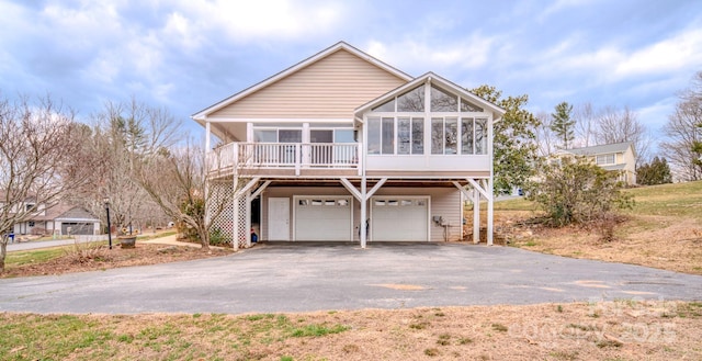 view of front facade featuring a garage, a sunroom, and aphalt driveway