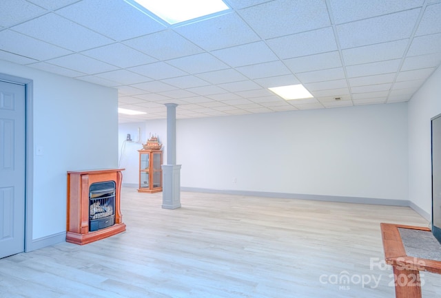 finished below grade area featuring light wood-style floors, a drop ceiling, and baseboards