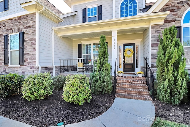 doorway to property featuring stone siding and covered porch