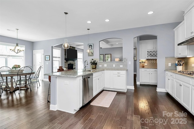 kitchen featuring decorative light fixtures, appliances with stainless steel finishes, white cabinets, a sink, and a peninsula