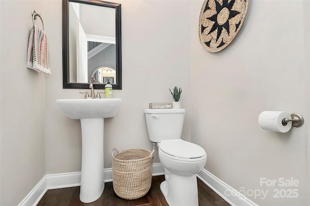 half bath featuring toilet, baseboards, and wood finished floors