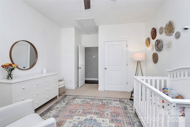 bedroom featuring attic access, light carpet, a crib, and baseboards