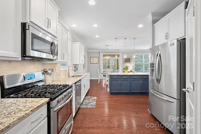 kitchen featuring white cabinets, blue cabinets, stainless steel appliances, pendant lighting, and a sink