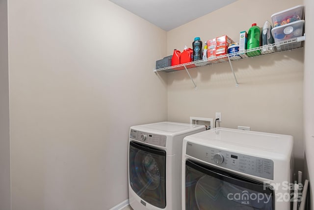 washroom featuring laundry area, washing machine and dryer, and baseboards