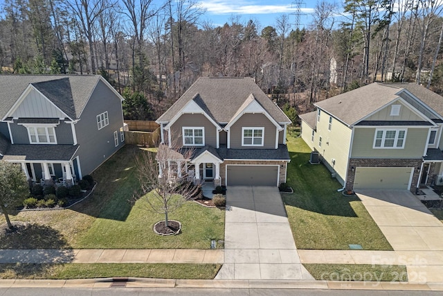 view of front facade featuring driveway, a shingled roof, an attached garage, and a front yard