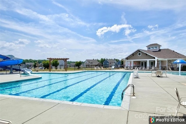 pool featuring a patio area, fence, a pergola, and a water slide