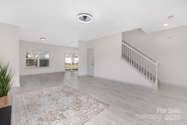 living room featuring stairs, wood finished floors, visible vents, and baseboards