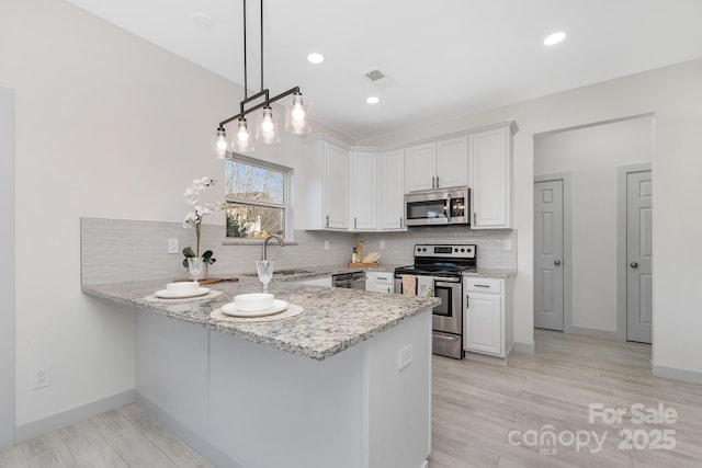 kitchen with light stone counters, stainless steel appliances, a peninsula, a sink, and visible vents