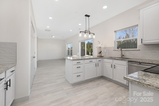 kitchen featuring tasteful backsplash, white cabinets, a sink, and a peninsula