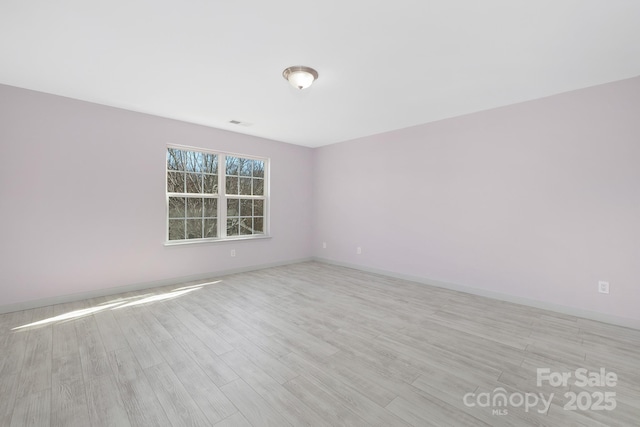 empty room with visible vents, baseboards, and wood finished floors