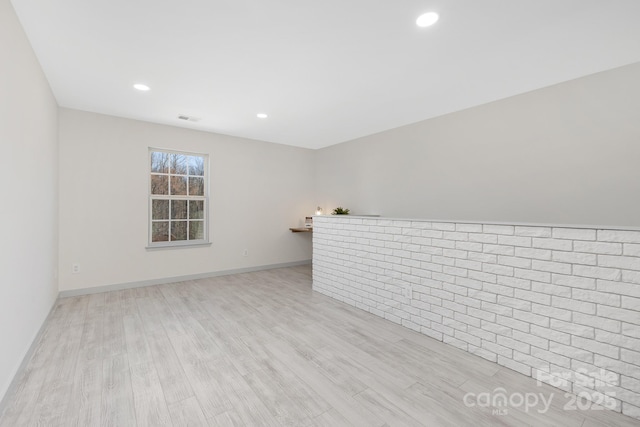 empty room with light wood finished floors, visible vents, baseboards, and recessed lighting