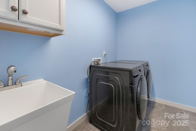 clothes washing area featuring washer and dryer, cabinet space, a sink, and baseboards