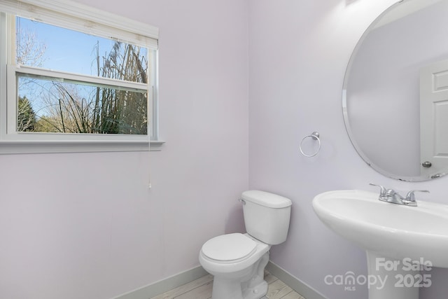 bathroom featuring baseboards, a sink, and toilet