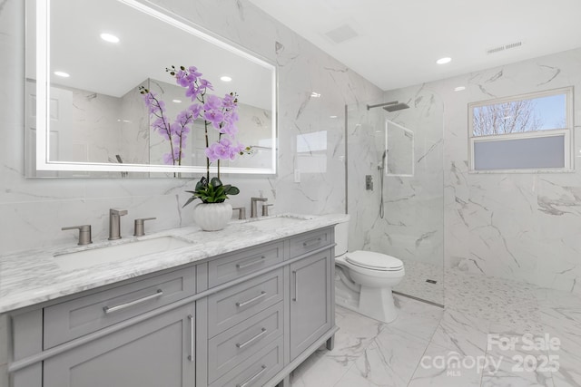 full bathroom with marble finish floor, a marble finish shower, a sink, and toilet