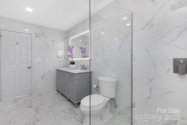 bathroom featuring stone wall, toilet, visible vents, vanity, and marble finish floor