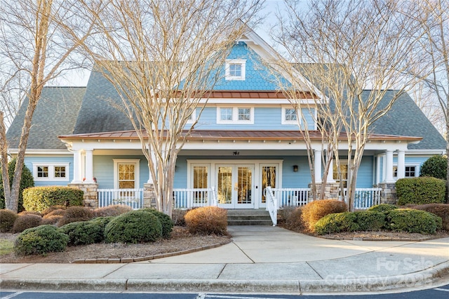 view of front of home featuring a shingled roof, covered porch, and french doors