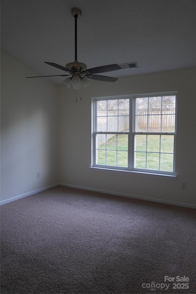 empty room with a healthy amount of sunlight, carpet flooring, and visible vents