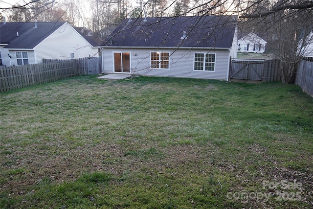 rear view of house with a gate, a fenced backyard, a yard, and a patio