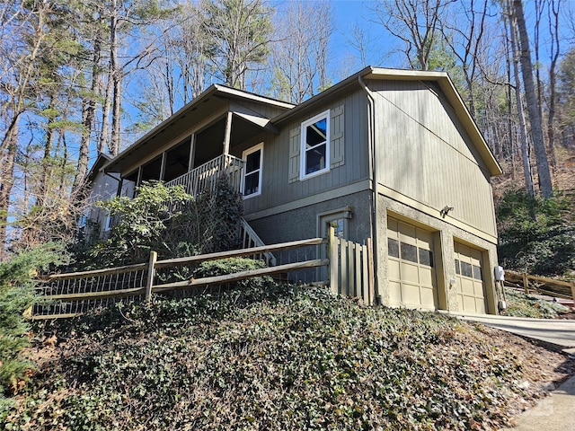 view of side of home with a garage, fence, and concrete driveway