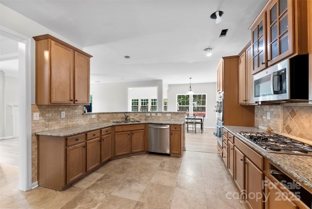 329 Squirrel Ln, Clover, SC 29710 - kitchen featuring stainless steel appliances, a peninsula, tasteful backsplash, brown cabinets, and recessed lighting