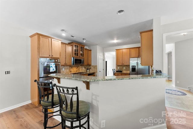 329 Squirrel Ln, Clover, SC 29710 - kitchen featuring appliances with stainless steel finishes, light stone countertops, decorative backsplash, a peninsula, and glass insert cabinets