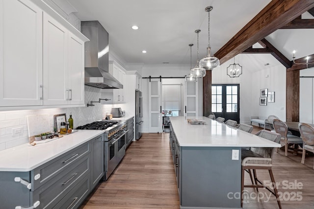 kitchen with a barn door, premium appliances, a kitchen breakfast bar, light countertops, and white cabinetry