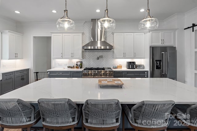 kitchen featuring premium appliances, pendant lighting, a large island, gray cabinets, and wall chimney exhaust hood