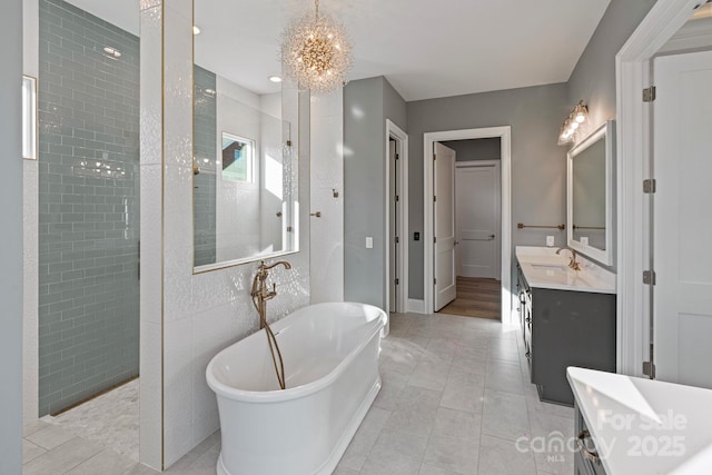 full bath with tile patterned floors, vanity, a freestanding tub, a chandelier, and a walk in shower