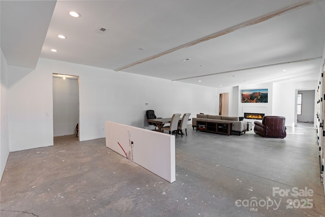 interior space with a lit fireplace, concrete floors, and recessed lighting