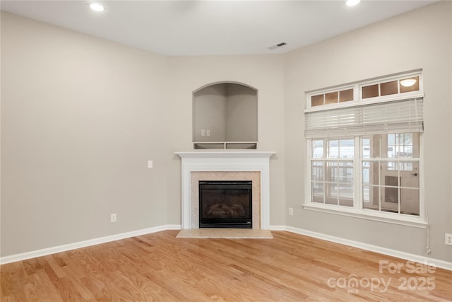 unfurnished living room featuring baseboards, a fireplace, visible vents, and wood finished floors